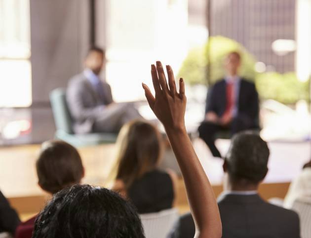 Hand in audience raised for a question at a business seminar Hand in audience raised for a question at a business seminar